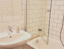 Badezimmer mit Wanne, Waschbecken und Spritzschutz in einer verkehrsg&uuml;nstig gelegenen Wohnung im 5.Bezirk in Wien